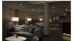 A modern lobby with a sofa, chairs, a round table, and a reception desk. - Casa Grande Suites (La Paz)