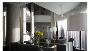 A modern living room with a sofa, a coffee table, and a lamp. There is a staircase leading to an upper level. - Casa Grande Suites (La Paz)