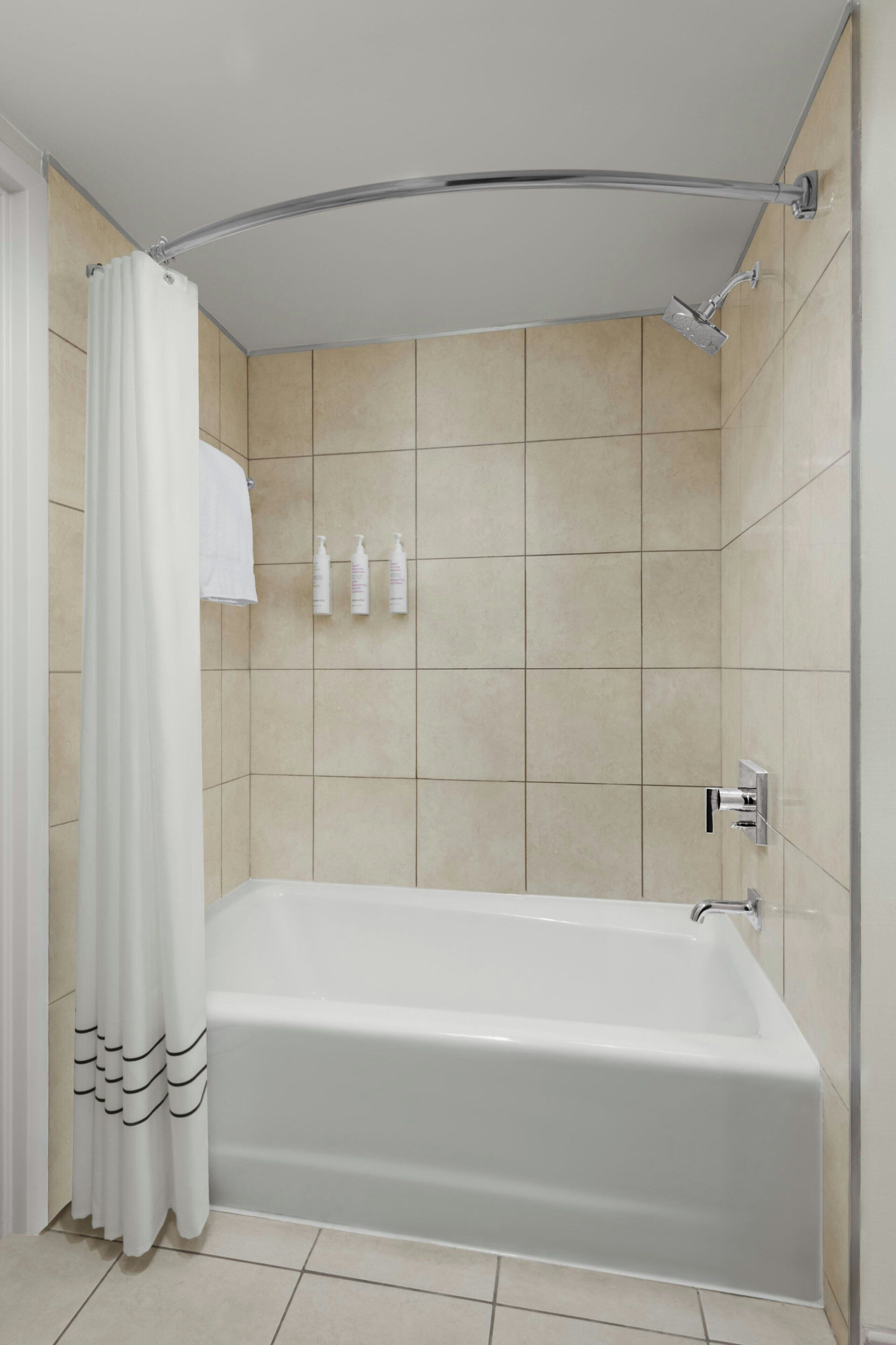 Een moderne badkamer met een badkuip, douche en betegelde wanden.