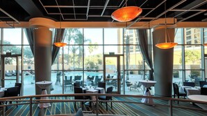 A hotel lobby with large windows, indoor pool, and dining area. - Anaheim Marriott Suites (Garden Grove)