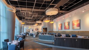A modern hotel lobby with a curved reception desk, seating areas, and artwork on the walls. - Anaheim Marriott Suites (Garden Grove)
