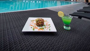 A Marriott Suites hotel with a swimming pool, a dining table with a plate of food and a drink, and lounge chairs. - Anaheim Marriott Suites (Garden Grove)