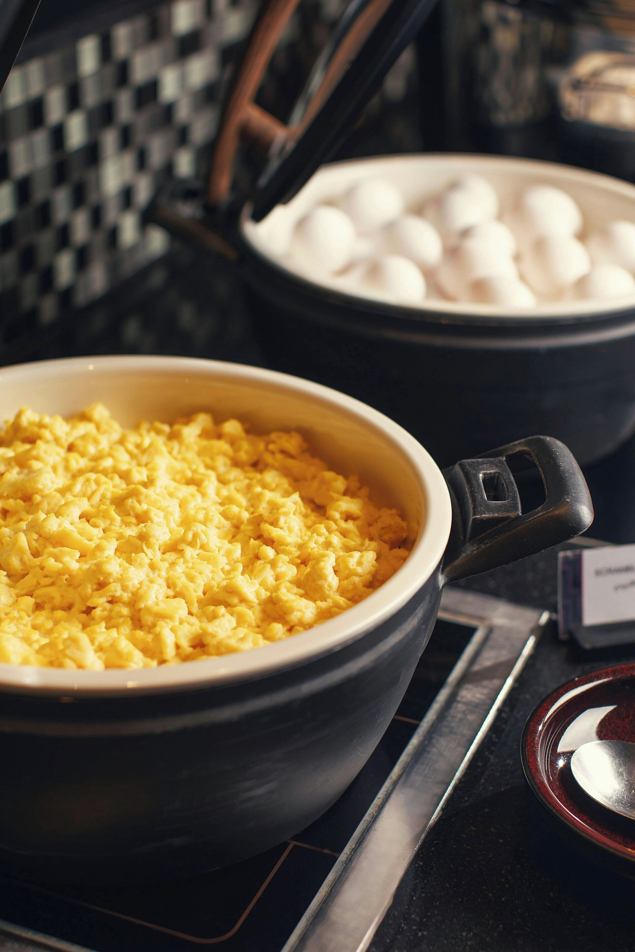A kitchen with a bowl of scrambled eggs and a pot of white balls, possibly potatoes, on a stove.