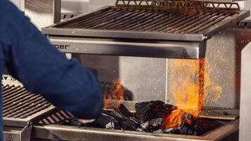 A grill with visible flames and sparks, indicating active cooking.