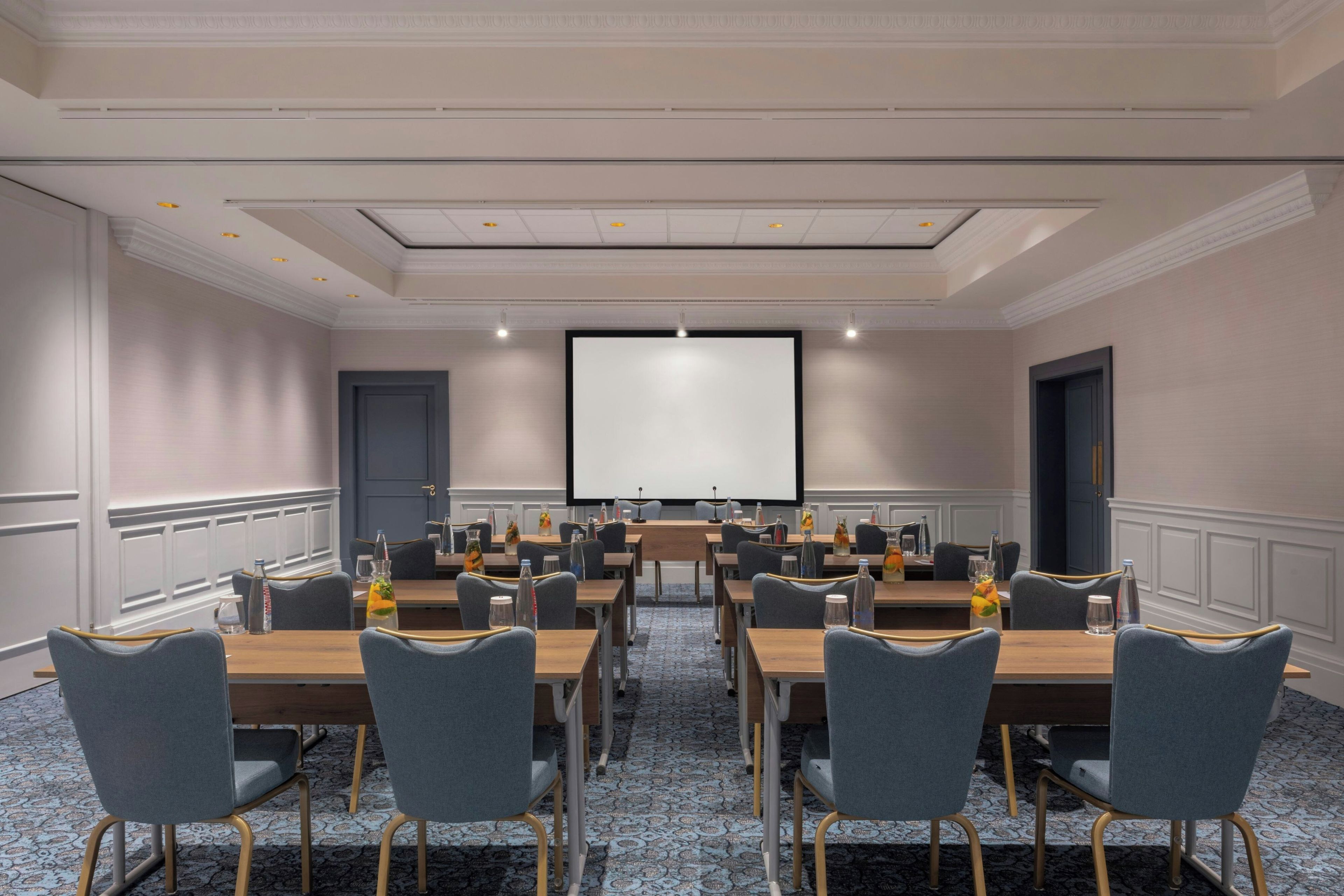 Une salle de conférence équipée d’un grand écran, de plusieurs tables et de chaises.