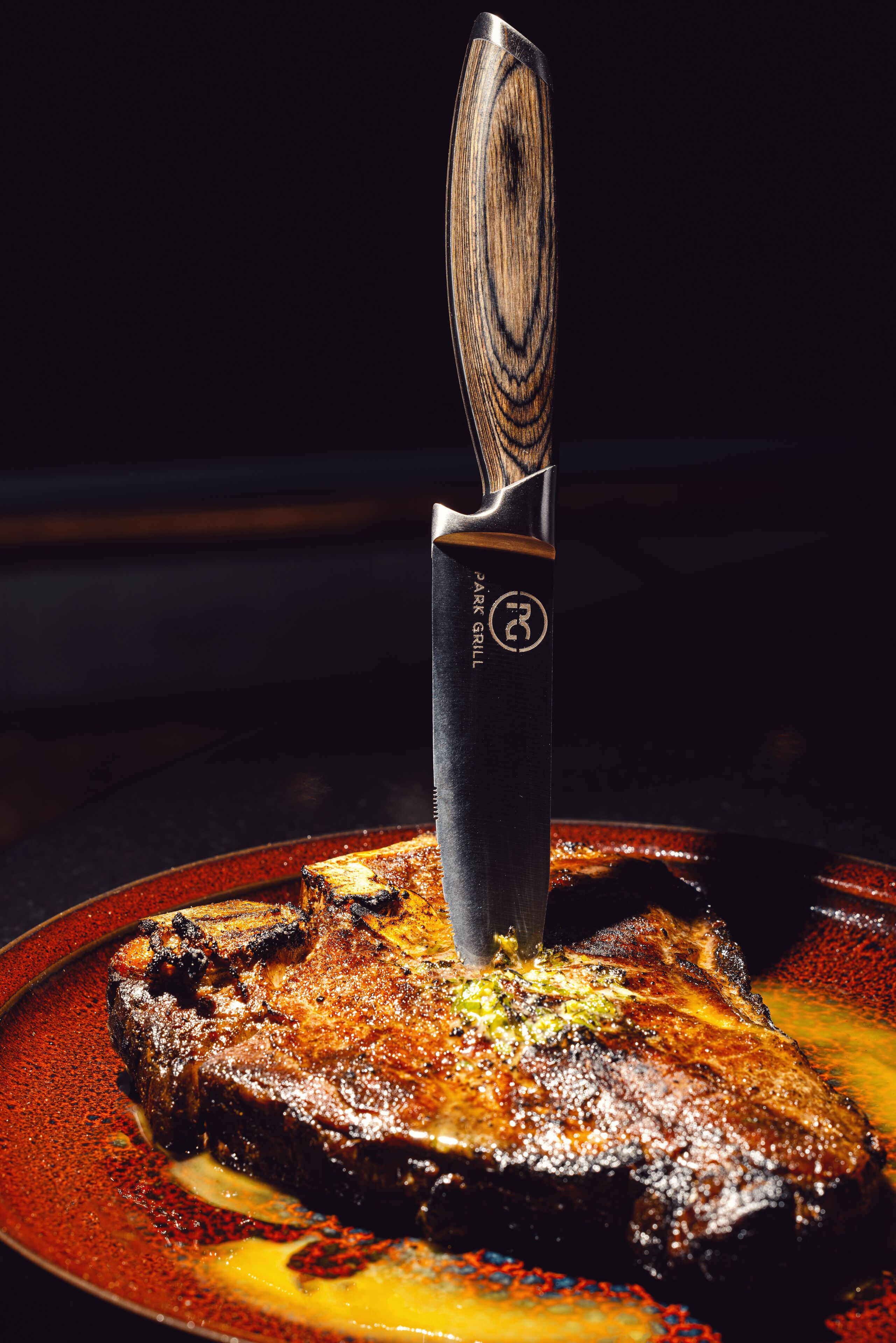 Un steak servi sur une assiette, avec un couteau à côté.