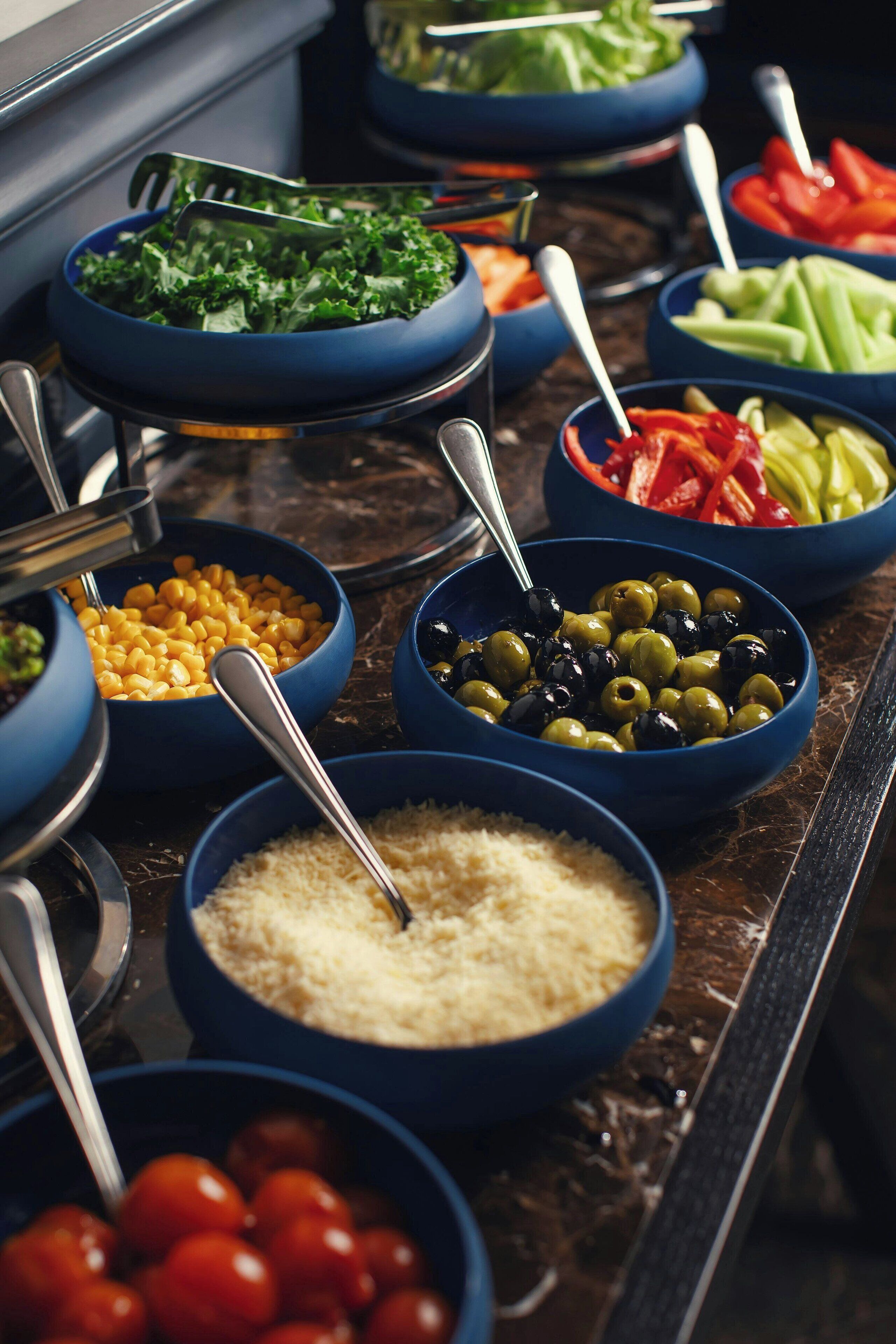 Een buffet met diverse soorten eten in blauwe schalen, zoals salades, groenten en granen.