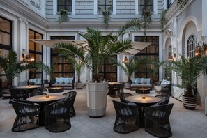 A spacious outdoor patio with round tables and chairs, surrounded by potted plants and large umbrellas. - Tbilisi Marriott Hotel (Tbilisi)