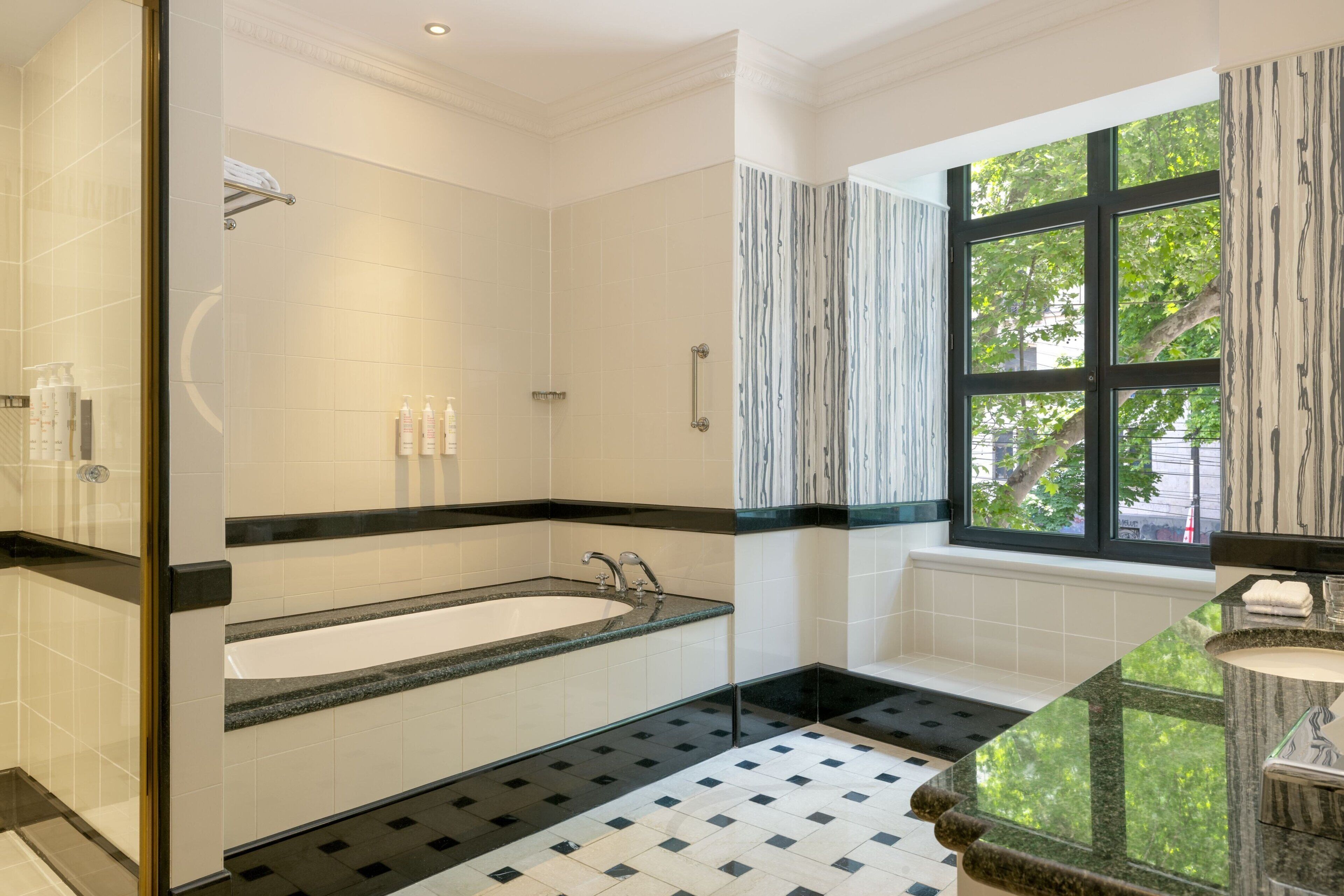 A modern bathroom with a freestanding bathtub, a shower area, and a window with curtains.