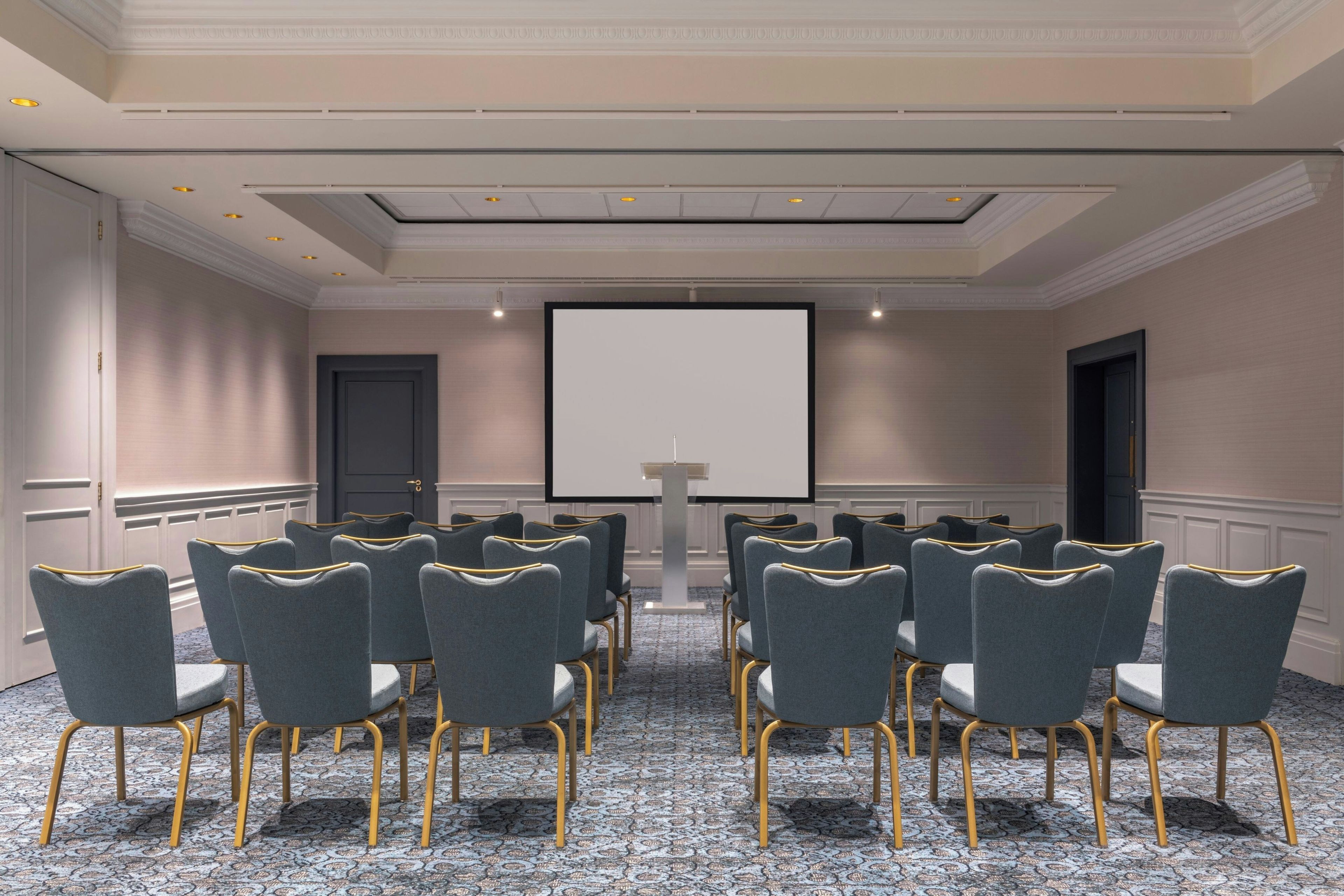 Uma sala de conferência com fileiras de cadeiras, uma tela de projeção e um pódio.