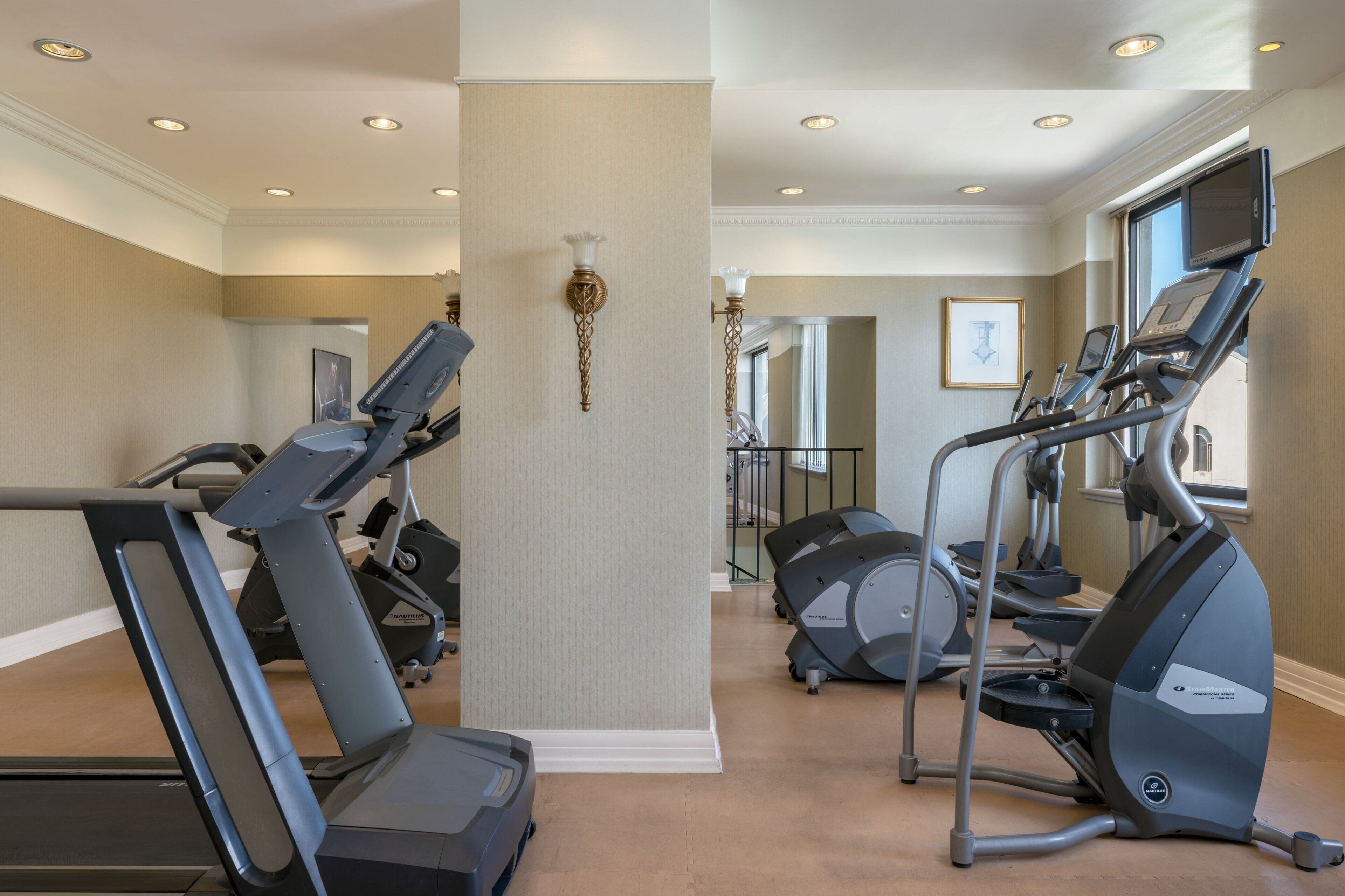 Een fitnessruimte met loopbanden, elliptische trainers en hometrainers.