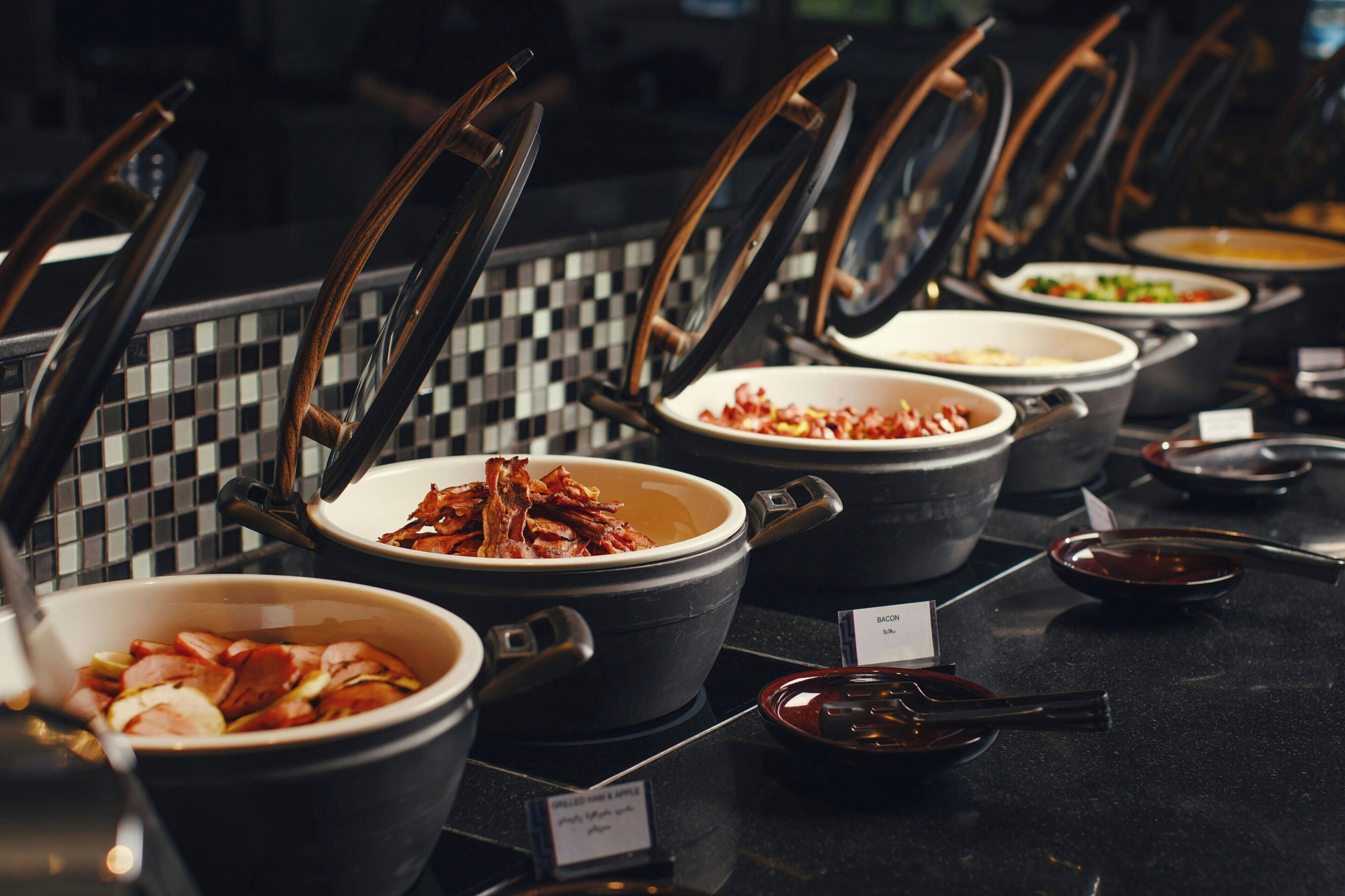 Un buffet proposant différents plats présentés dans des plats, chacun étant accompagné d’une étiquette indiquant le nom du plat.