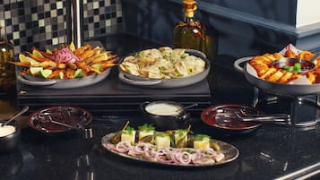 A buffet table with various dishes, including seafood, dumplings, and cheese.