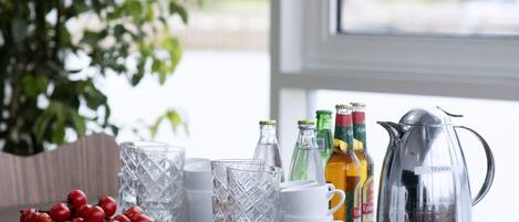 A table with a plate of strawberries, a pitcher, and bottles of beverages.