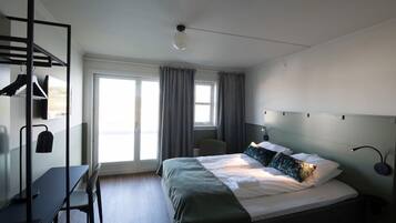 Ein modernes Hotelzimmer mit Bett, Schreibtisch und Stuhl.