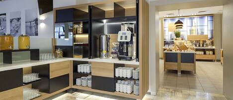 Una cocina moderna con una estación de café integrada, un refrigerador y un comedor con mesa y sillas.