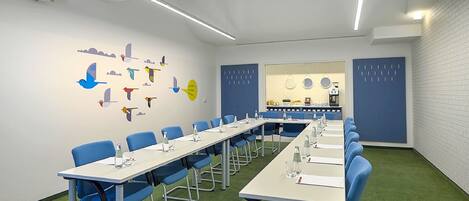 A conference room with a long table, blue chairs, and a wall with colorful bird decals.