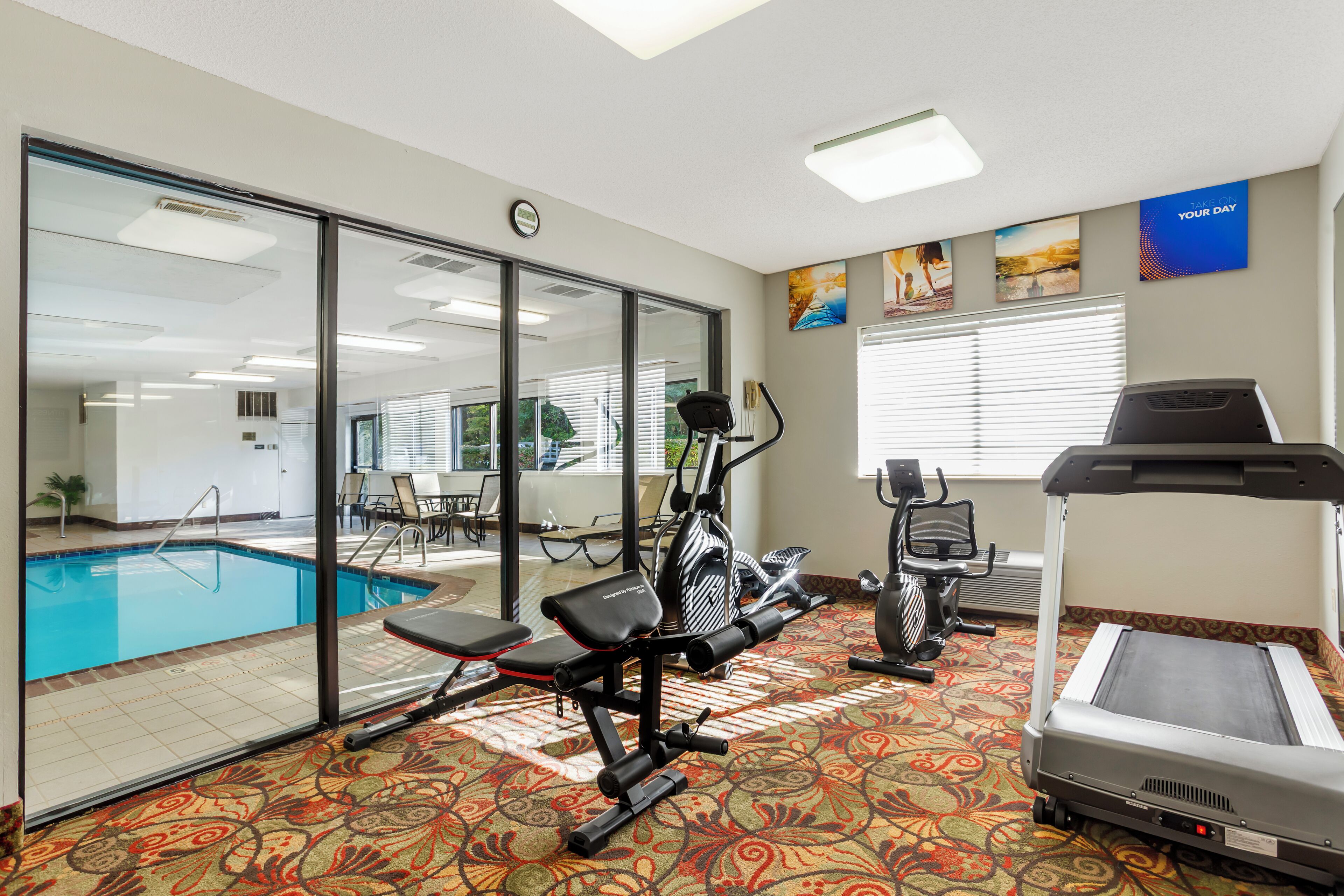Un gimnasio con equipo de ejercicio, piscina y cinta de correr.