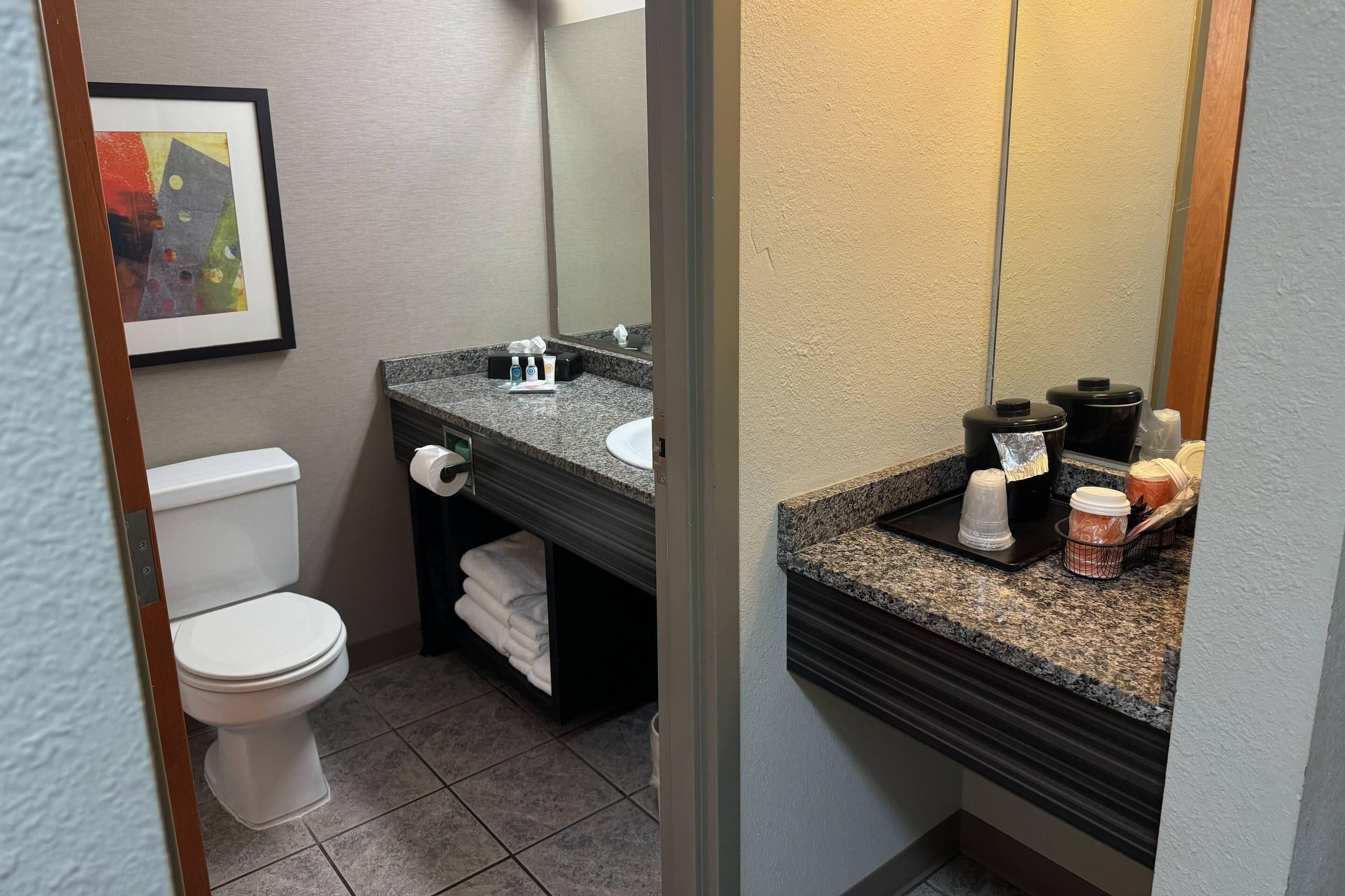 A bathroom with a white toilet, a sink with toiletries, and a mirror.