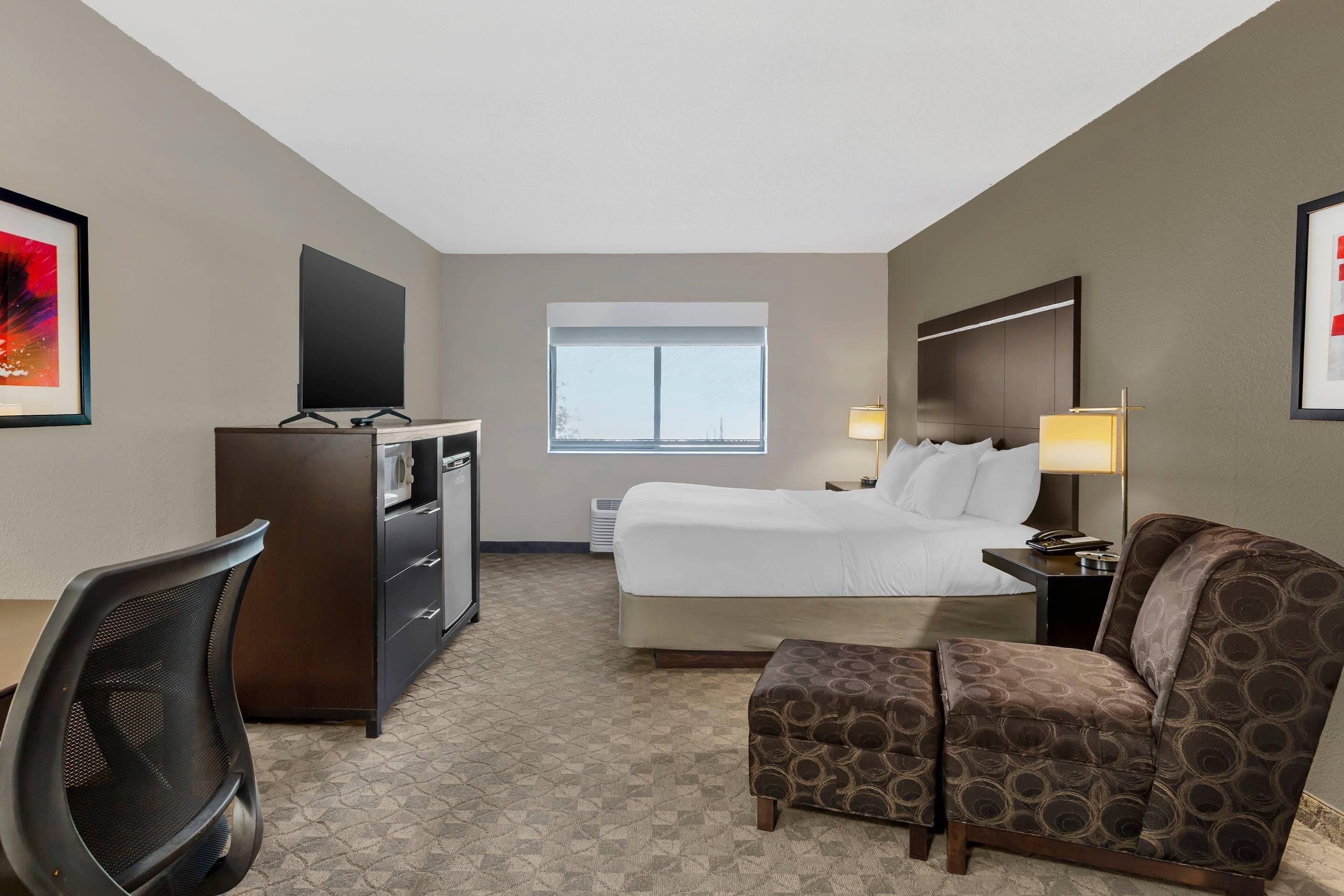 Une chambre d’hôtel équipée d’un lit, d’un bureau, d’une chaise et d’un téléviseur.