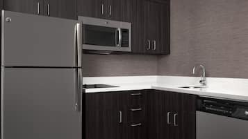 A modern kitchen with dark wood cabinets, stainless steel appliances, and a white countertop.
