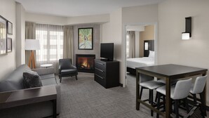 A hotel room with a sofa, armchair, TV, fireplace, dining table, and chairs. - Residence Inn by Marriott Charlotte SouthPark (Charlotte)