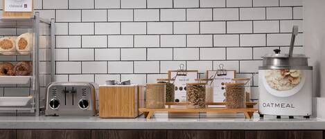 Una encimera de cocina con un tostador, una cafetera y varios recipientes de comida.