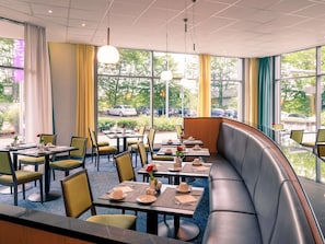 Un ristorante con tavoli e sedie, una panca e ampie finestre che offrono vista all'esterno.