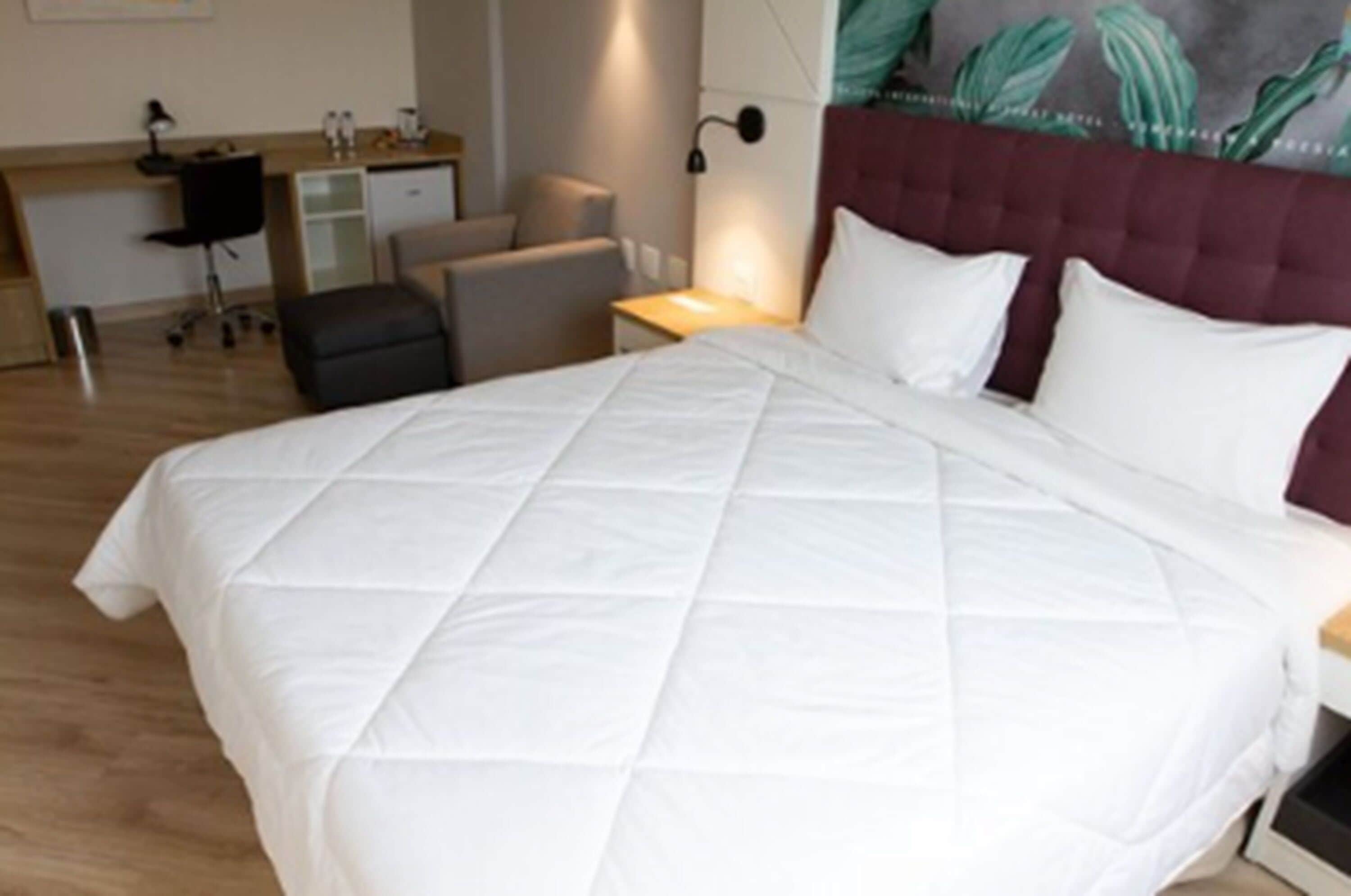 Una habitación de hotel con una cama grande, un escritorio y una silla.