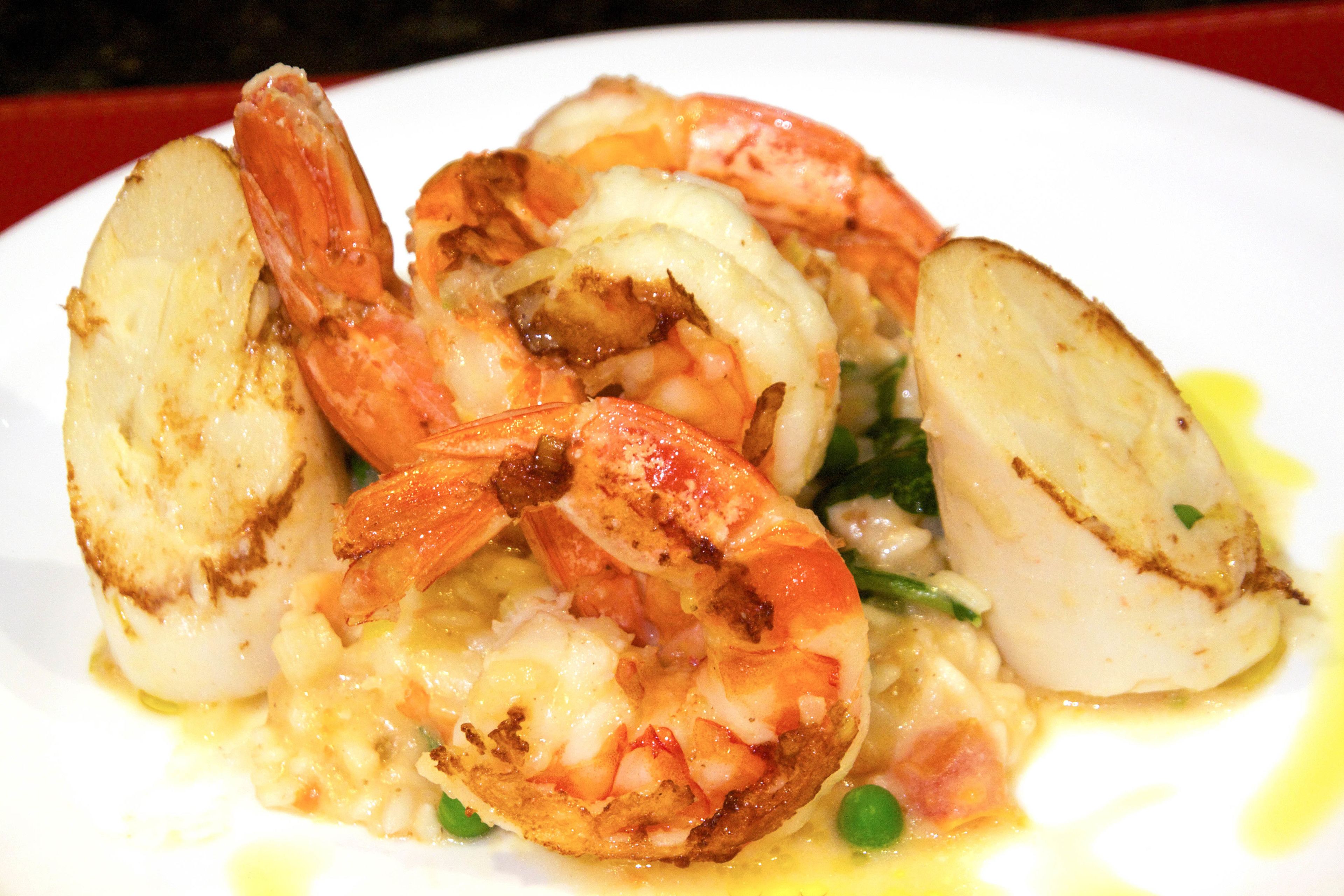 A plate of cooked shrimp with potatoes and peas.