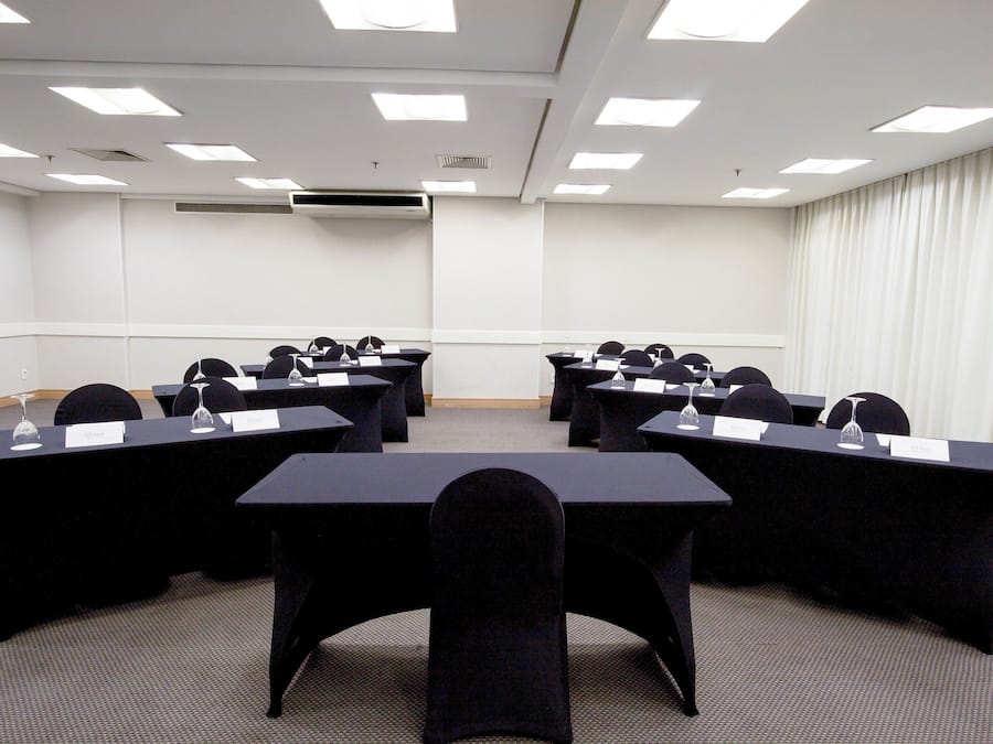 A conference room with multiple tables and chairs, equipped with nameplates and water glasses.