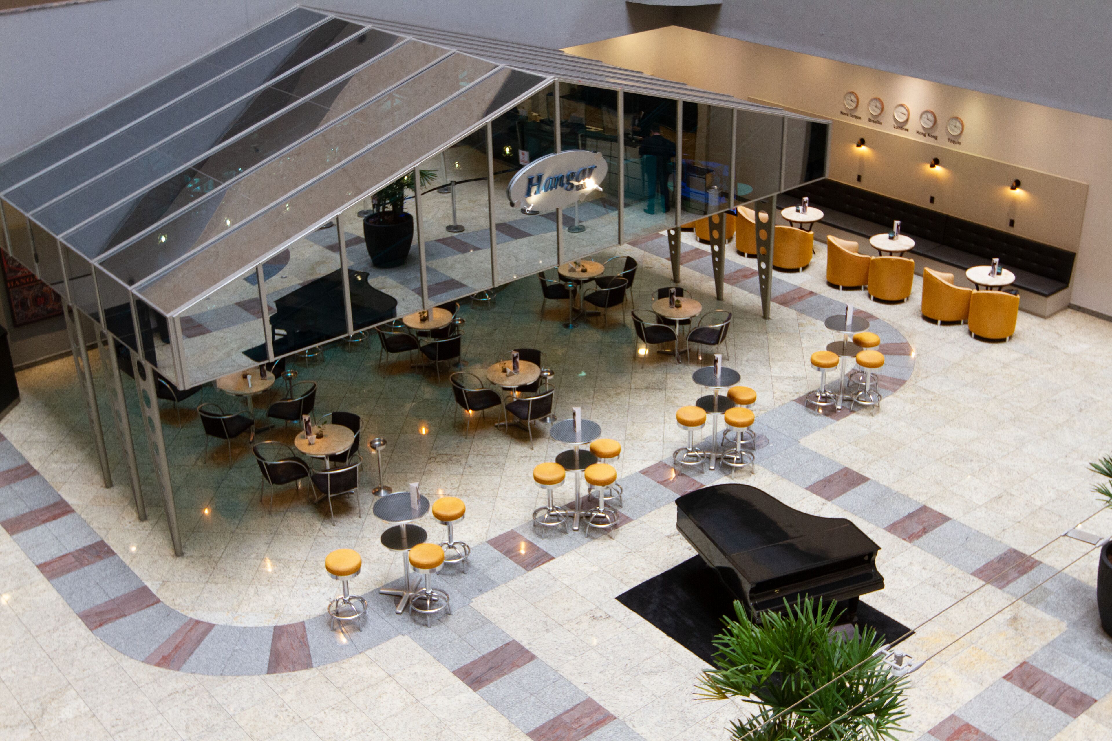 A spacious indoor area with multiple tables and chairs, a piano, and a glass-enclosed section.