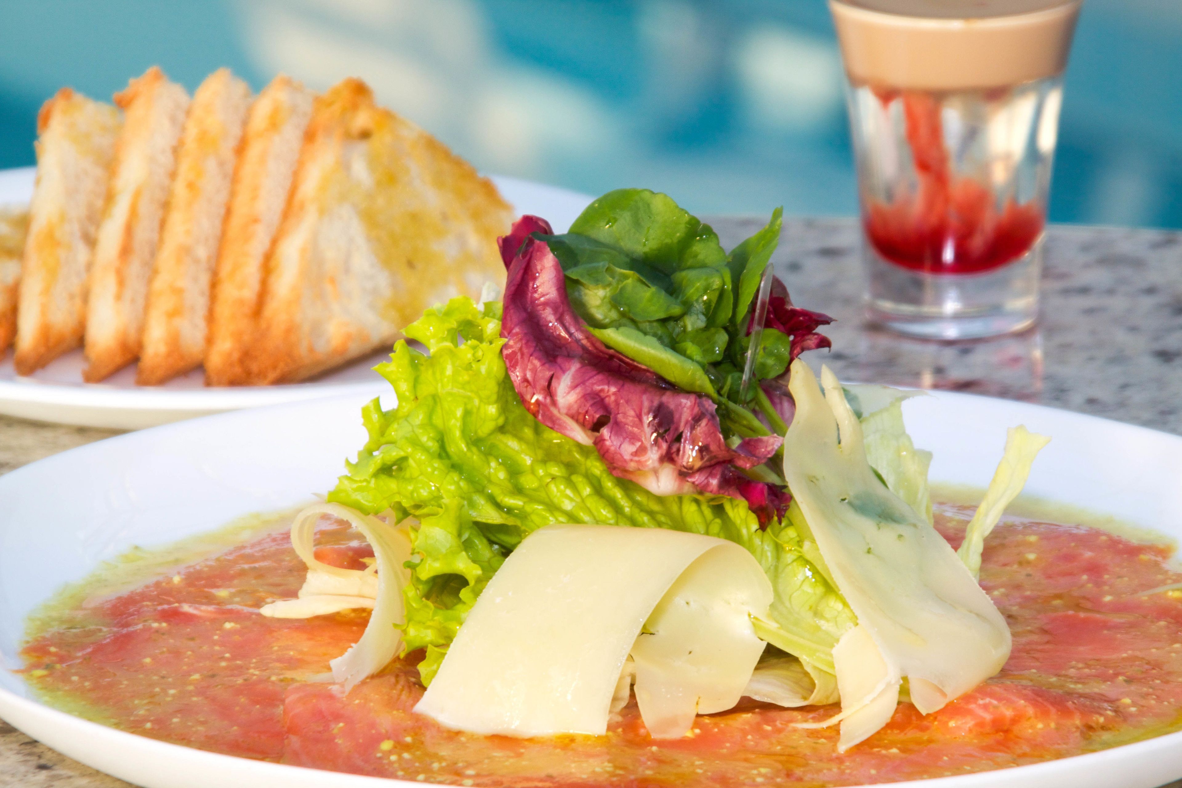 Um prato de comida com salada, uma fatia de pão e um copo de água.
