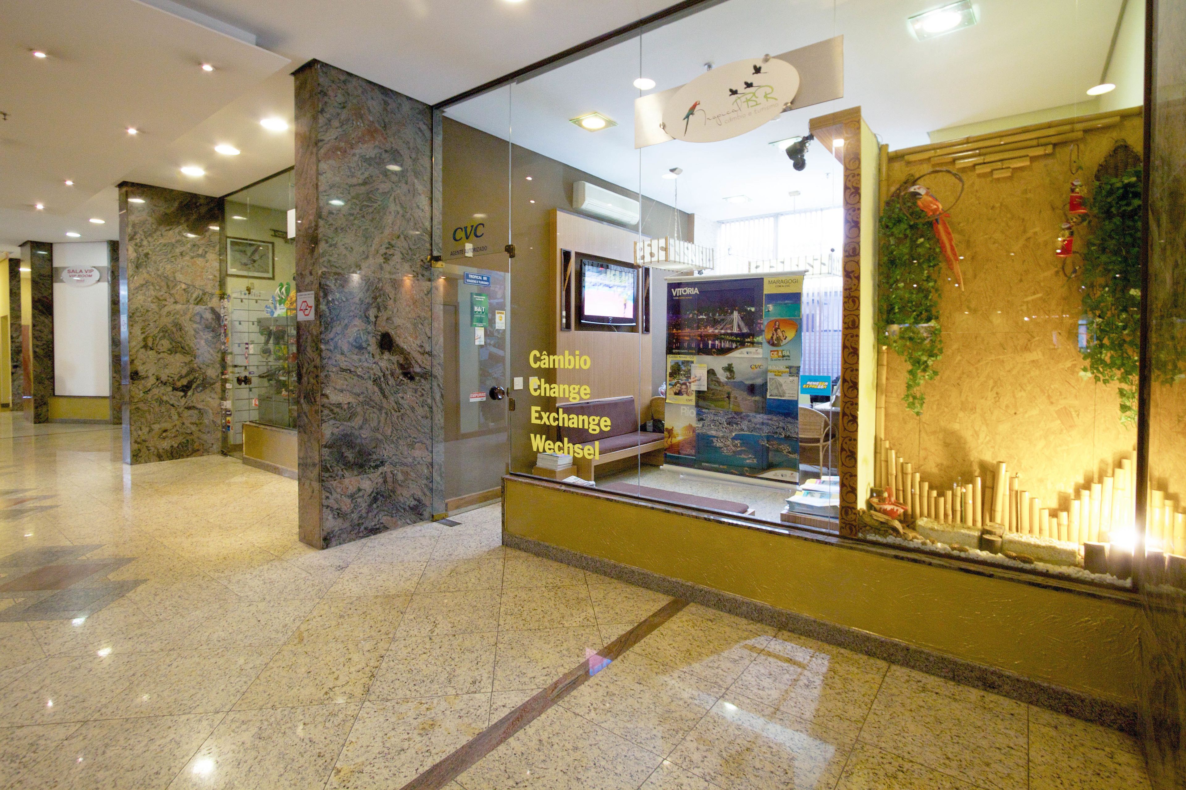 A lobby with marble columns, a reception desk, and a glass wall displaying a poster.