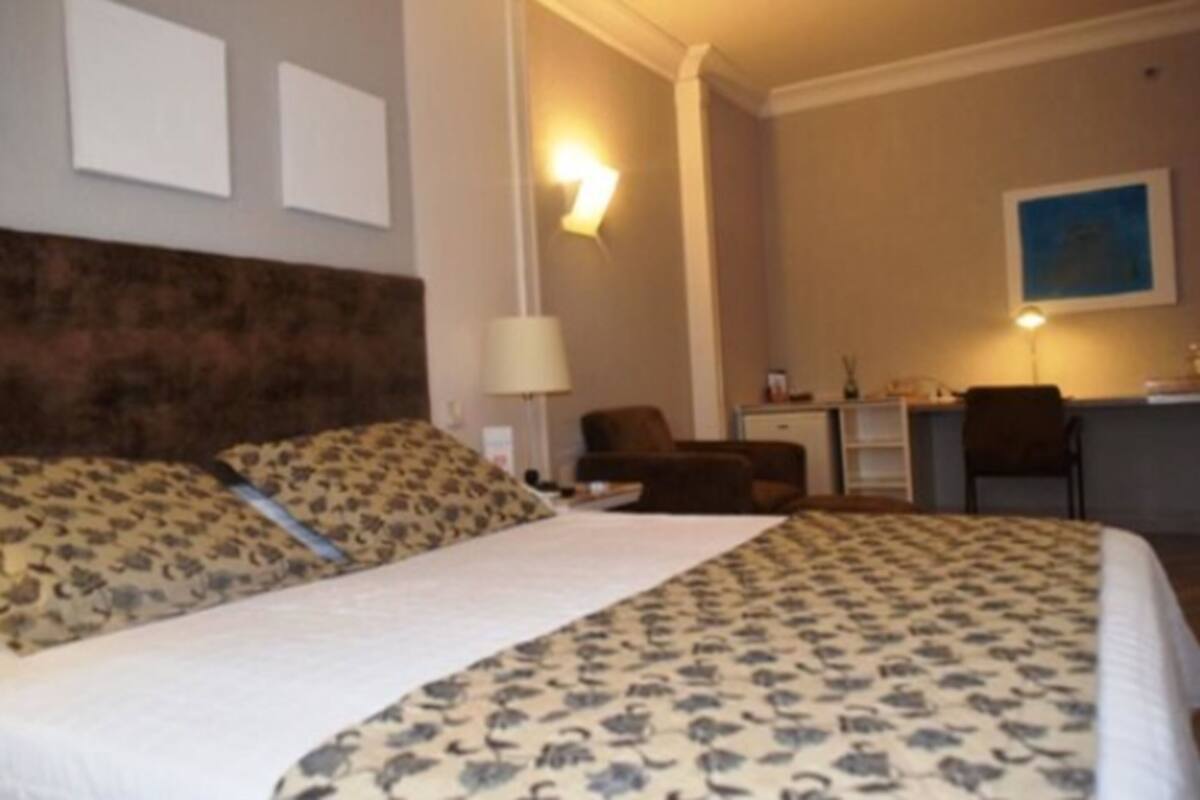 Hotellihuone, jossa on sänky, työpöytä, tuoli ja lamppu.
