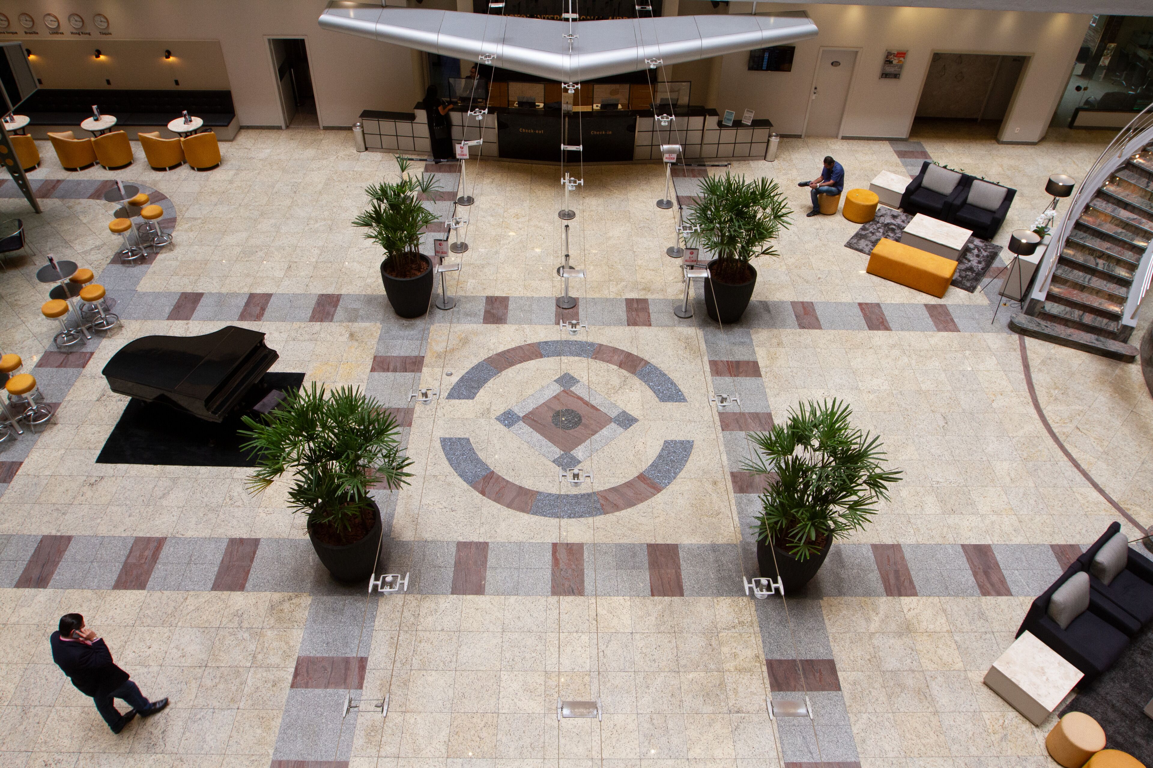 A spacious lobby with a check-in counter, seating areas, and a central decorative tile pattern.