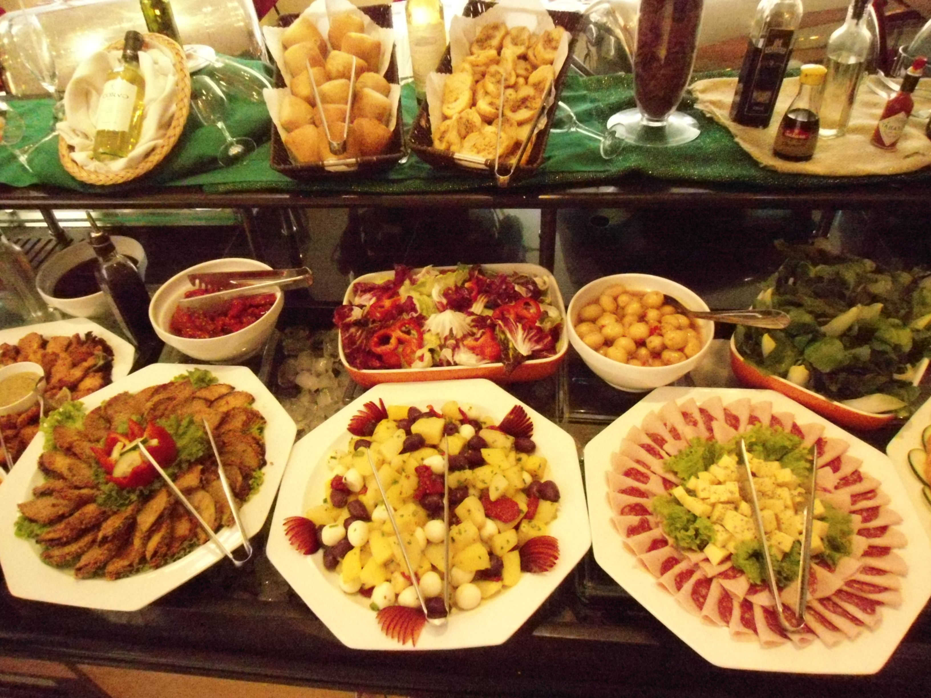 Un bufé con diversos platos, incluyendo ensaladas, frutas y carnes.