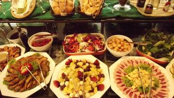Un bufé con diversos platos, incluyendo ensaladas, frutas y carnes.