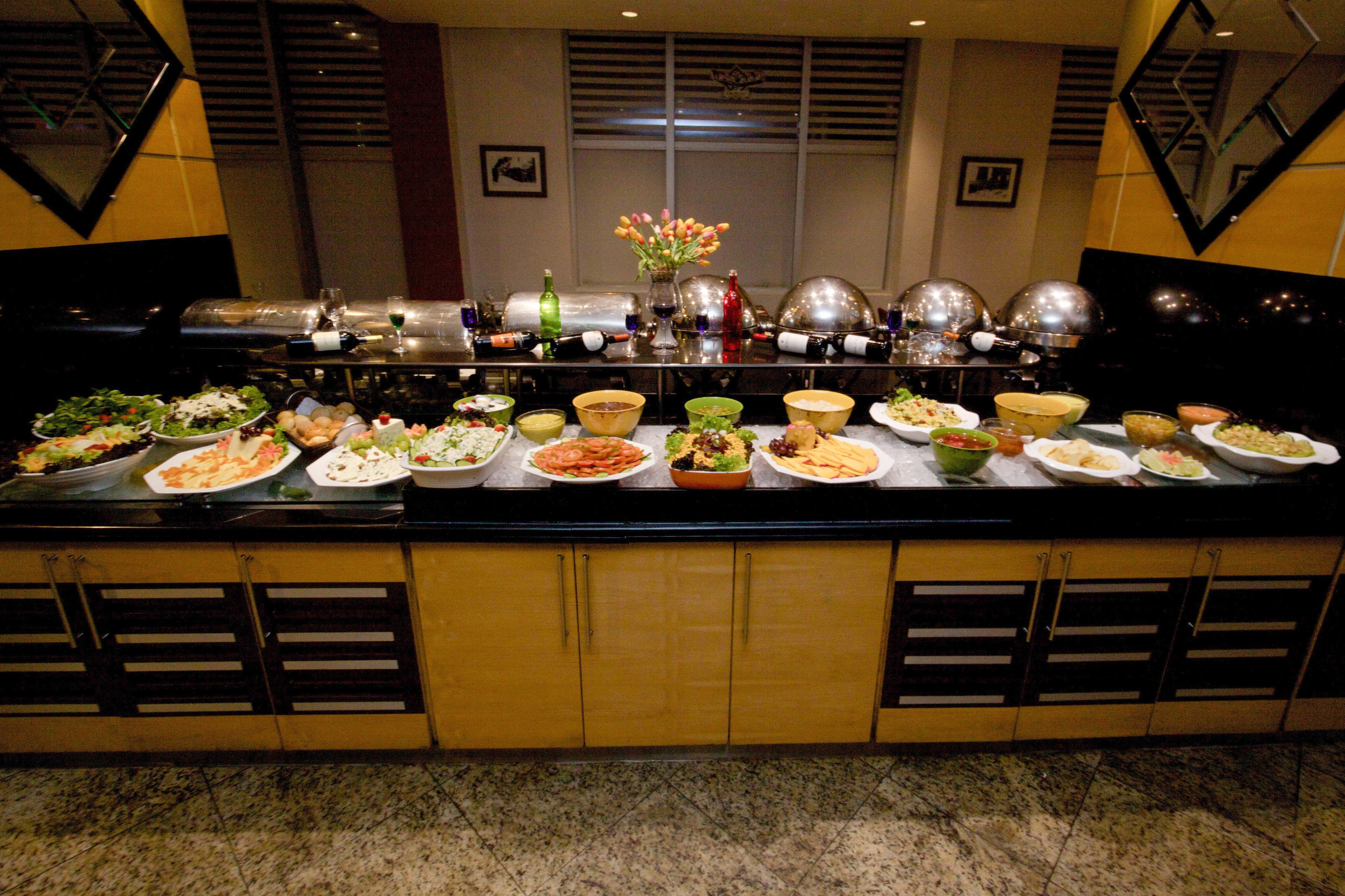A buffet with various dishes and a vase of flowers.
