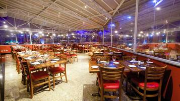 Un restaurante espacioso con numerosas mesas y sillas, ventanas amplias y un techo alto.