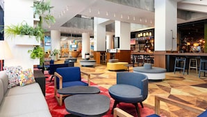 A spacious lobby with seating areas, a bar, and a television screen.