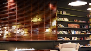 A modern lounge area with a checkered armchair, a sofa, a small round table, and a bookshelf filled with books.