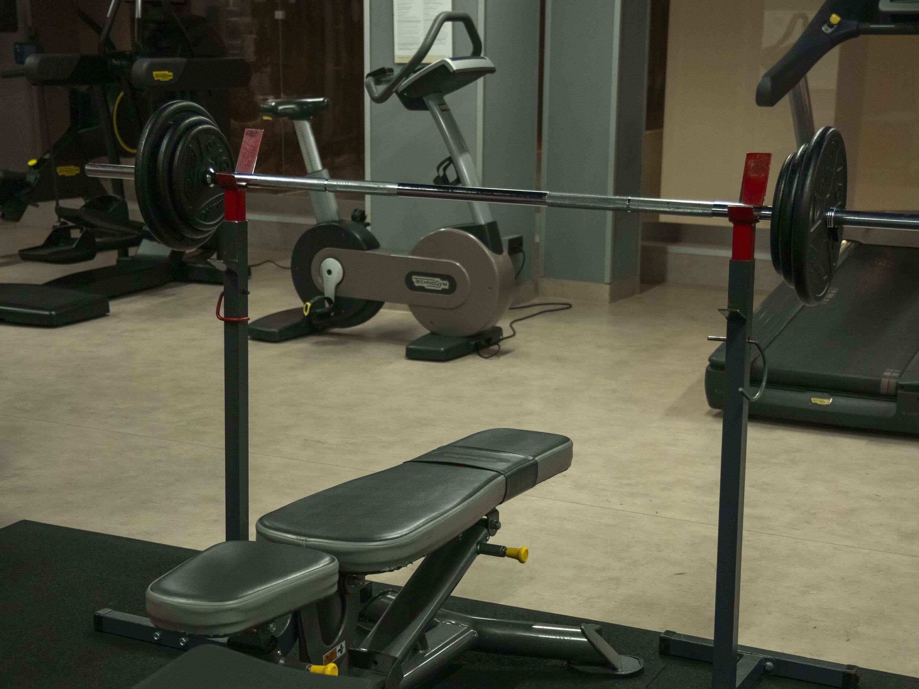 A gym with exercise equipment, including a bench press and a treadmill.