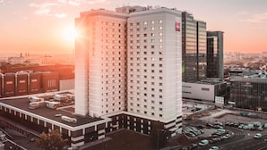 A high-rise hotel with a modern design, featuring a prominent 'ibis HOTEL' sign at the top.