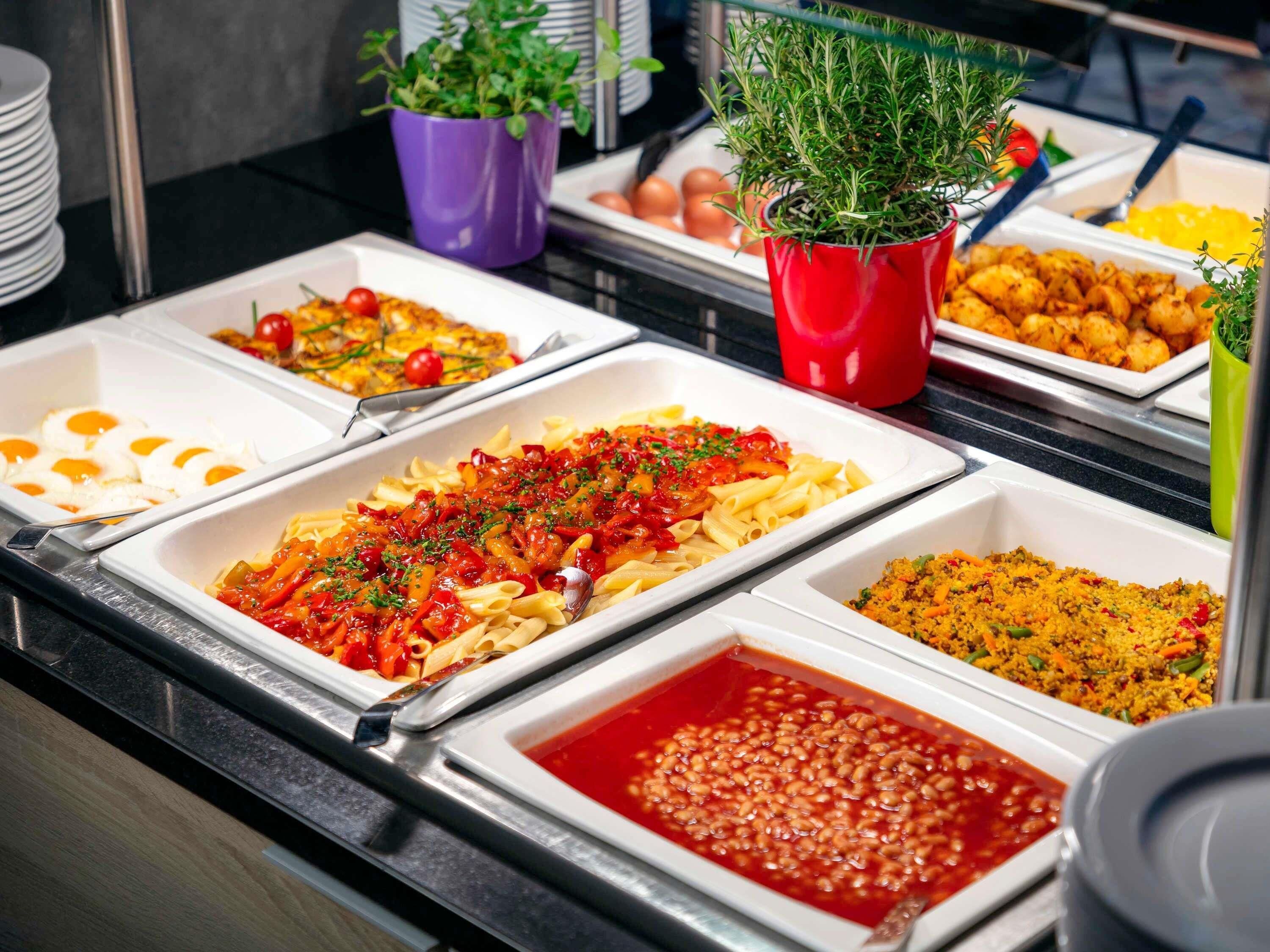 A buffet with various dishes including pasta, eggs, and beans.