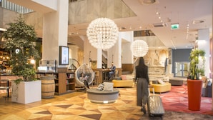 A spacious lobby with a central seating area, a reception desk, and a staircase leading to upper floors.