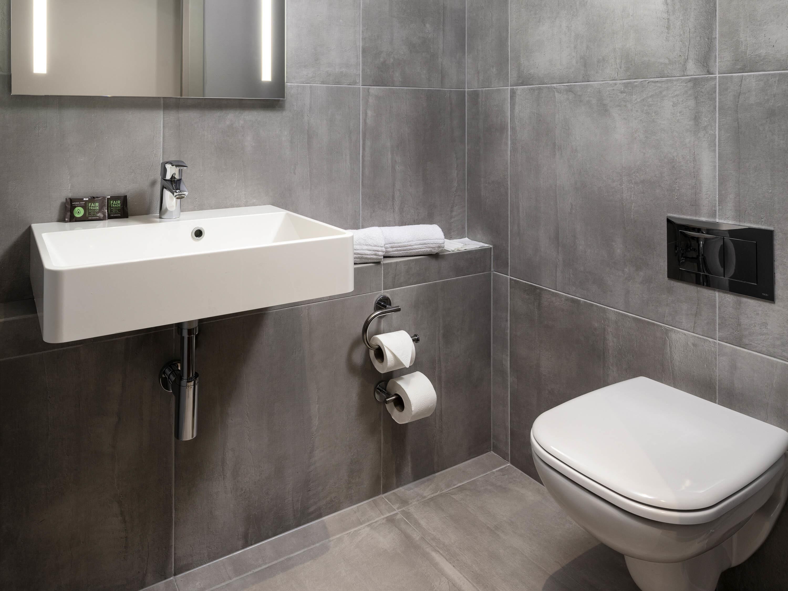 Un baño moderno con un lavamanos blanco, inodoro y un perchero para toallas.