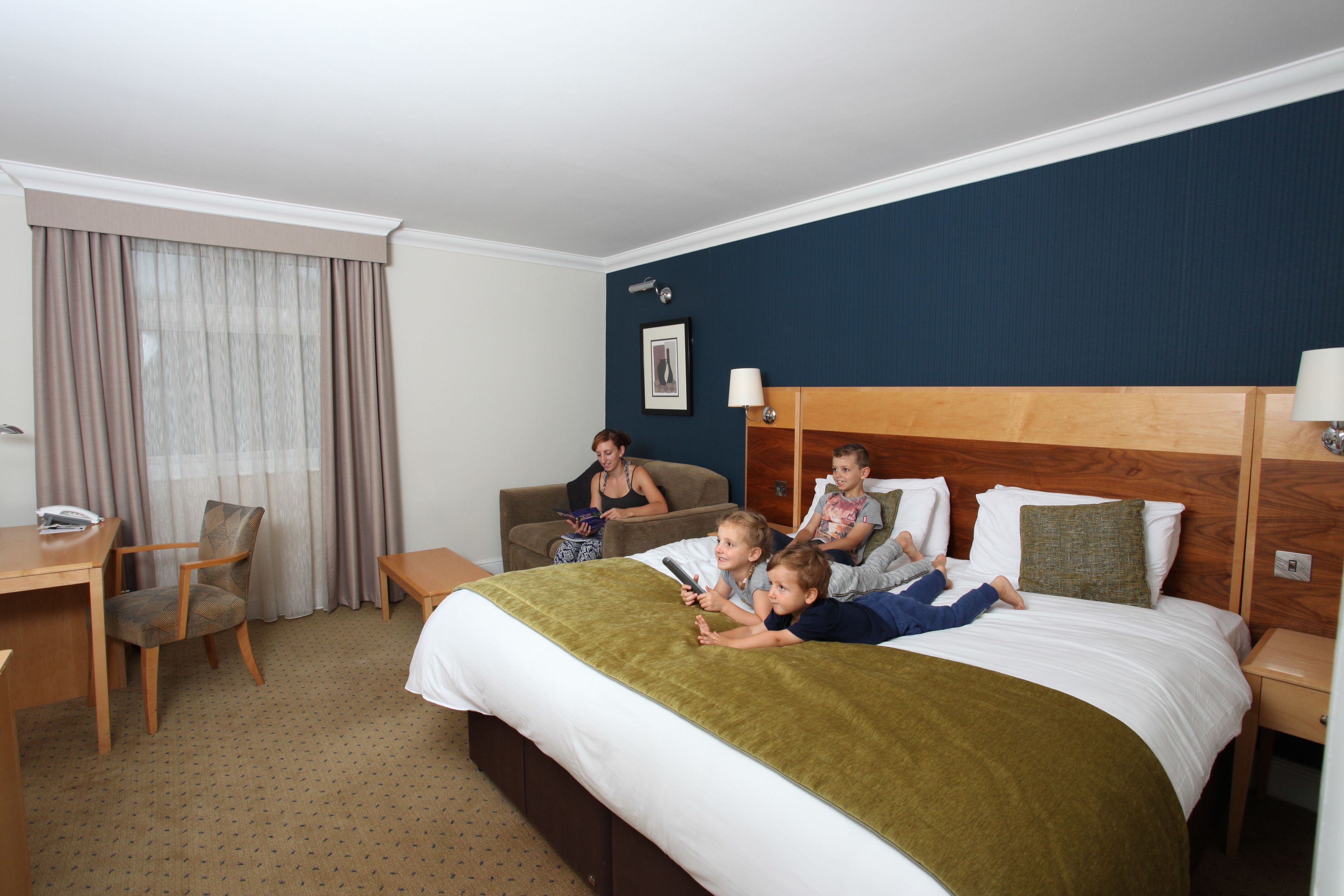 Una habitación de hotel con una cama, un escritorio, una silla y una ventana con cortinas.
