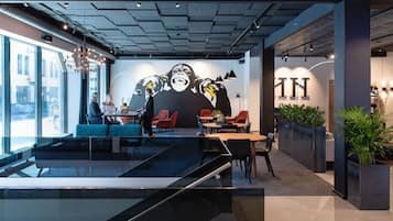 A modern interior with a large mural, seating areas, and a glass pool.