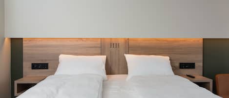 Una cama doble con cabecera de madera, dos mesitas de noche con controles y un control remoto sobre una de ellas.